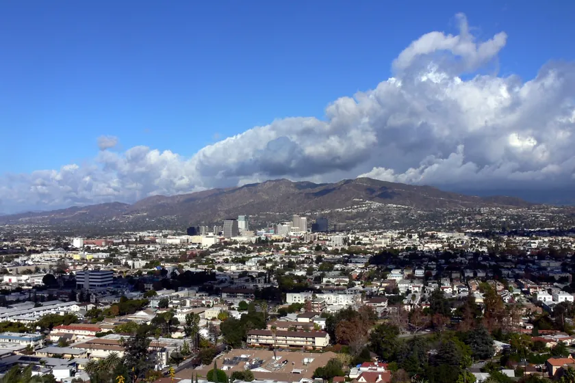 Glendale's neighborhoods and downtown towers spread below the Verdugo Mountains under billowing white clouds