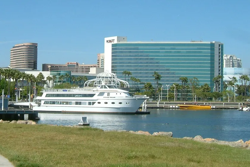 Downtown Long Beach's waterfront, with a white tour boat docked in the harbor below the hotels and office towers