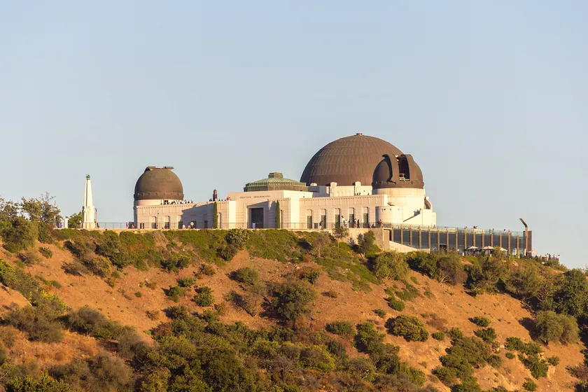 Griffith Observatory's white Art Deco domes on the brush-covered slope of Mount Hollywood in Los Angeles