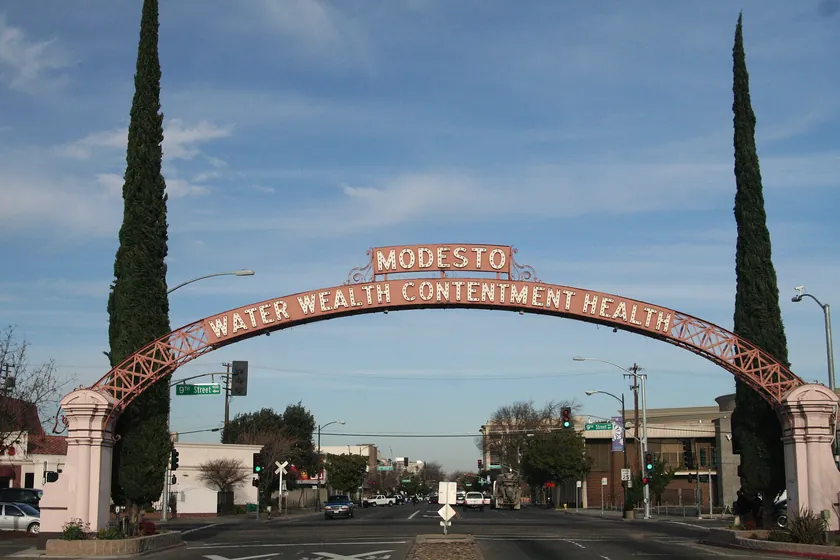 The historic Modesto Arch spanning a downtown street, lettered with the city motto Water, Wealth, Contentment, Health