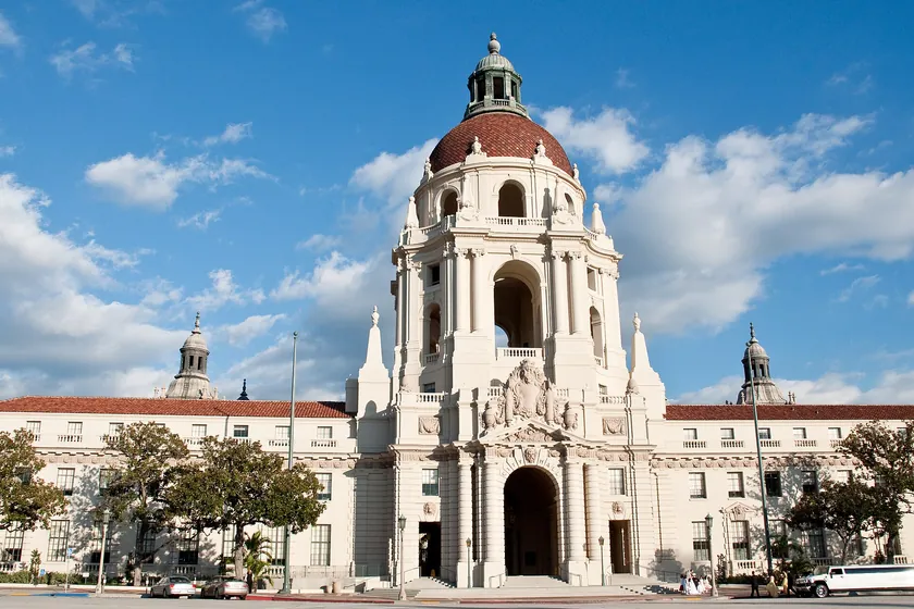 Pasadena City Hall's domed tower and Spanish Revival arches under a bright blue sky with scattered clouds