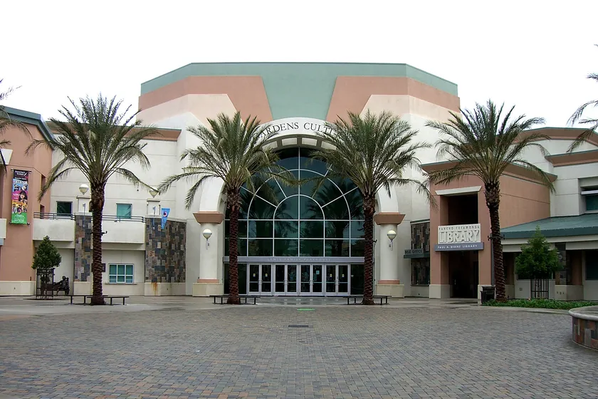 The arched glass entrance of the Victoria Gardens Cultural Center and library, framed by palm trees, in Rancho Cucamonga
