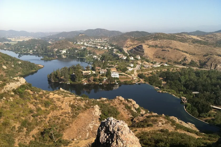 Lake Sherwood and its hillside homes seen from a rocky peak, with the hills toward Hidden Valley beyond, near Thousand Oaks